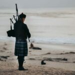 image of a long-haired piper singing on a beach by the sea.