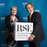 from the left, Professor Donna Heddle and Professor Jason König holding a cube with the RSE branding.