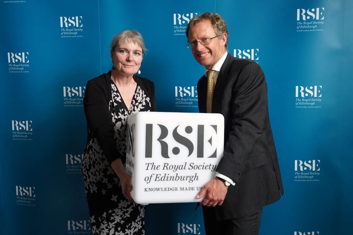 from the left, Professor Donna Heddle and Professor Jason König holding a cube with the RSE branding.